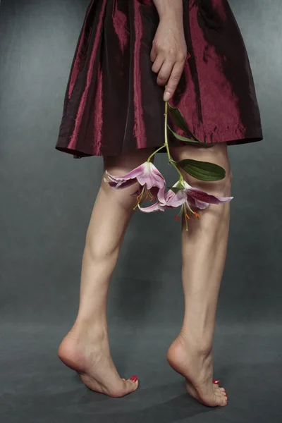 De benen van de vrouw met rode satijnen jurk over grijs — Stockfoto