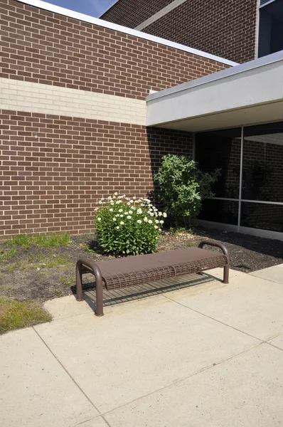 Empty bench by a school building — Stock Photo, Image