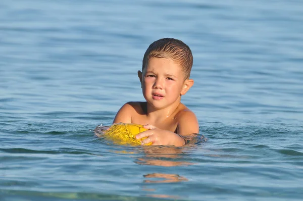 Мальчик на пляже играет с мячом — стоковое фото