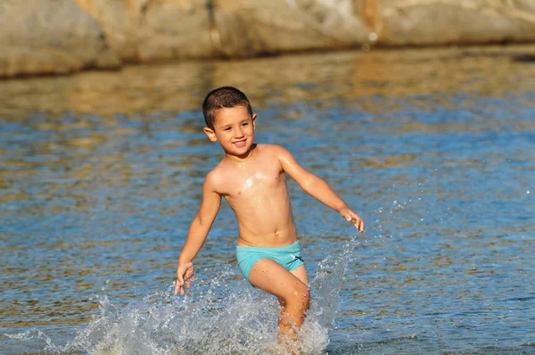Niño jugando en la playa y las olas — Foto de Stock
