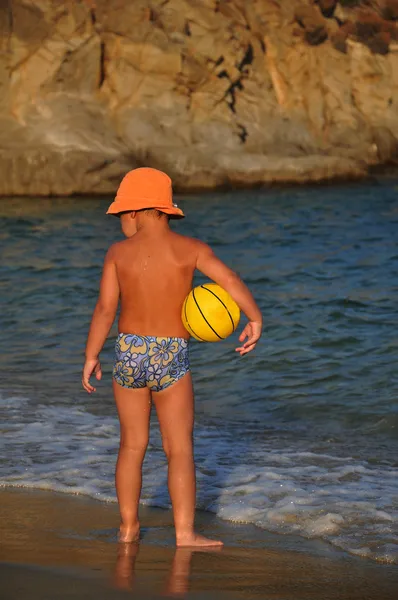 Хлопчик на пляжі грає з м'ячем — стокове фото