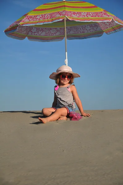 Meisjes op het zandstrand onder een parasol — Stockfoto