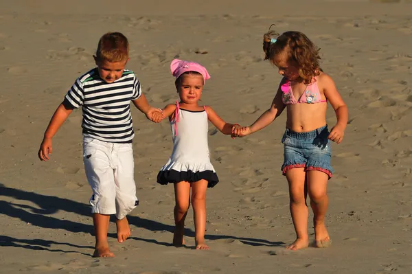 Duas meninas e um menino brincando na areia da praia — Fotografia de Stock