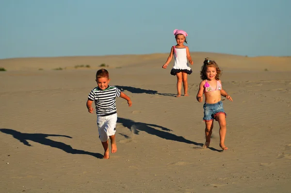 Δύο κορίτσια και ένα αγόρι που παίζει στην άμμο παραλία — Φωτογραφία Αρχείου