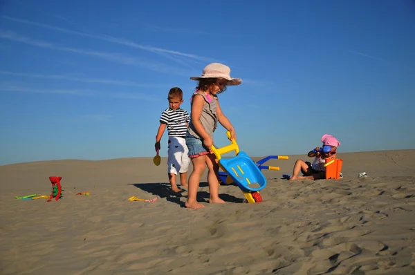 Dvě holky a kluk hraje na písku pláže — Stock fotografie