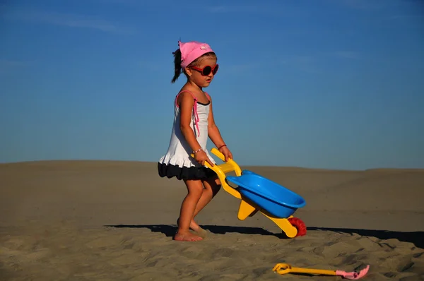 Güzel, küçük bir kız oynamak ve sahilde atlama — Stok fotoğraf