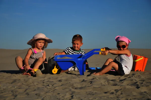 Dos chicas y un chico jugando en la arena de la playa —  Fotos de Stock