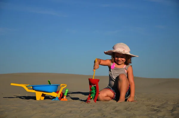 En vacker liten flicka spela och hoppa på stranden — Stockfoto