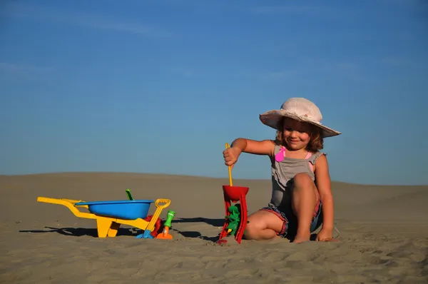 Красивая маленькая девочка играет и прыгает на пляже — стоковое фото