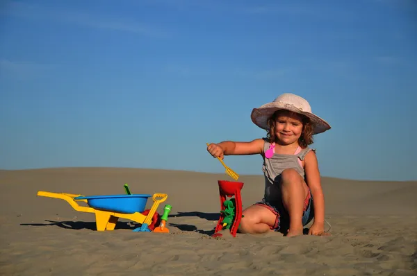 Een mooi klein meisje spelen en springen op het strand — Stockfoto