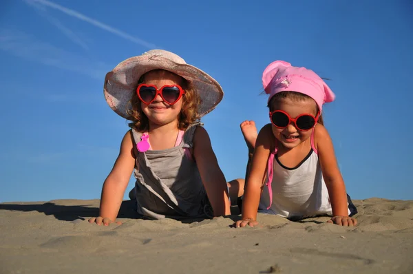 A homokos tengerparton fekvő két kislány — Stock Fotó