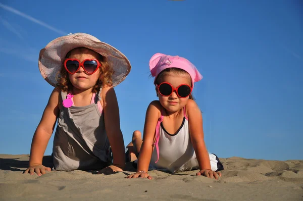 Two little girls lying on the sandy beach — Stock Photo, Image