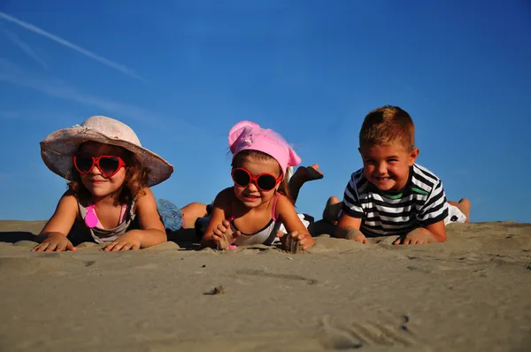 Två små flickor och en pojke som ligger på sandstranden — Stockfoto