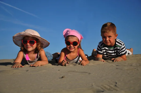 Дві маленькі дівчата і хлопчик лежать на піщаному пляжі — стокове фото