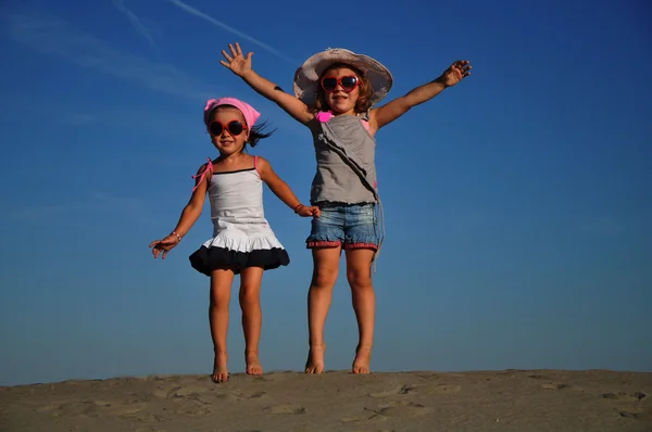 Two happy little girl jumping on the beach — Stock Photo, Image