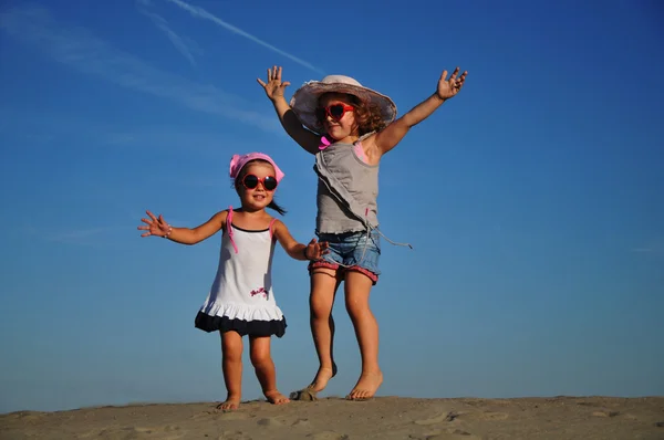 Дві щасливі дівчинки стрибають на пляжі — стокове фото