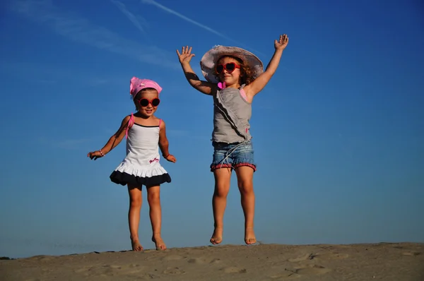 Zwei glückliche kleine Mädchen springen am Strand — Stockfoto