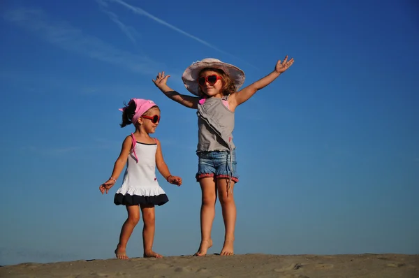 Két boldog kislány ugrál a parton. — Stock Fotó