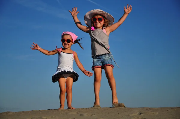 Kumsalda zıplayan iki mutlu küçük kız. — Stok fotoğraf