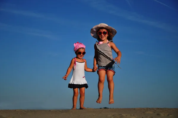Két boldog kislány ugrál a parton. — Stock Fotó