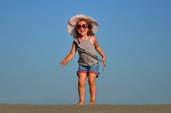 Uma linda menina brincar e saltar na praia — Fotografia de Stock