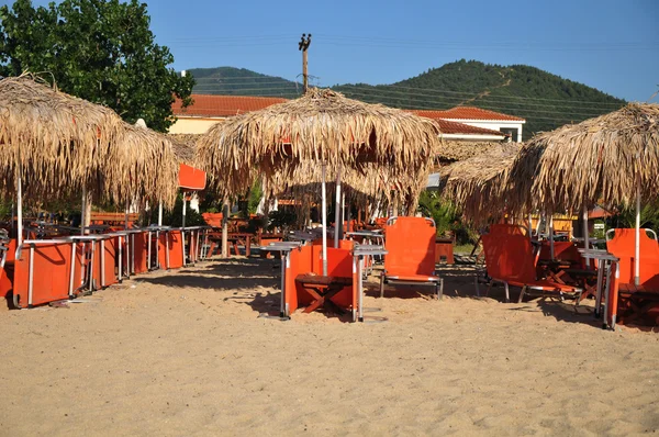 Många vita randiga solstolar och parasoller finns på tom strand. — Stockfoto