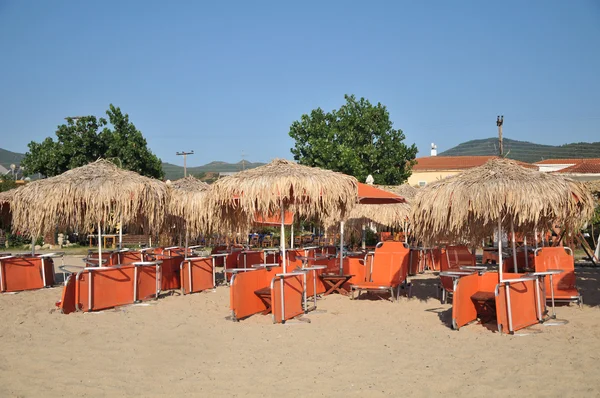 Sok fehér csíkos nyugágyak és napernyők üres strandon. — Stock Fotó