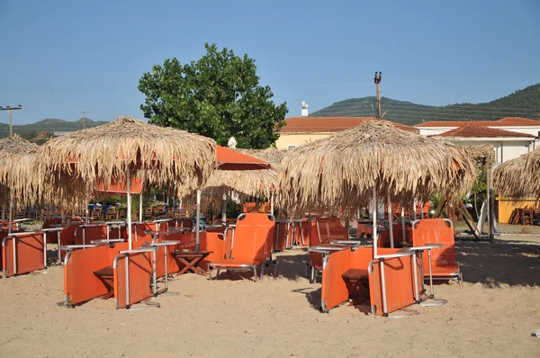 Багато білих смугастих стільців і пляжних парасольок знаходяться на порожньому пляжі . — стокове фото