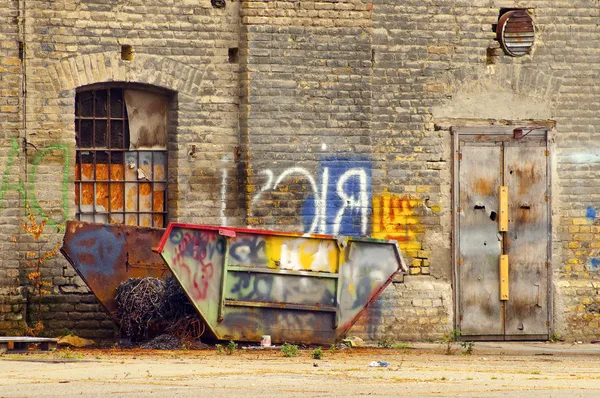 Stary uszkodzony pojemnik na podwórku budynku przemysłowym — Zdjęcie stockowe