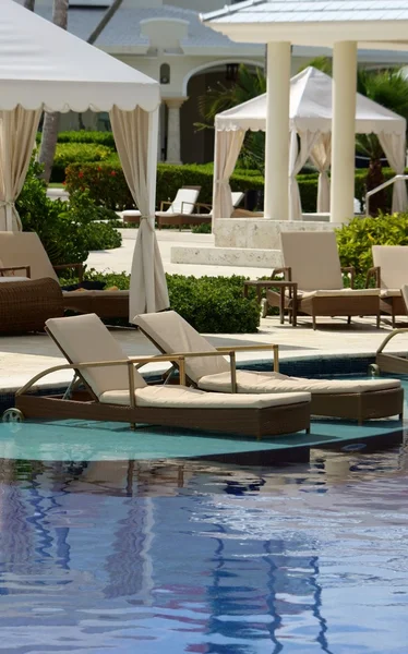 Ligstoelen in pool van luxe tropisch resort — Stockfoto