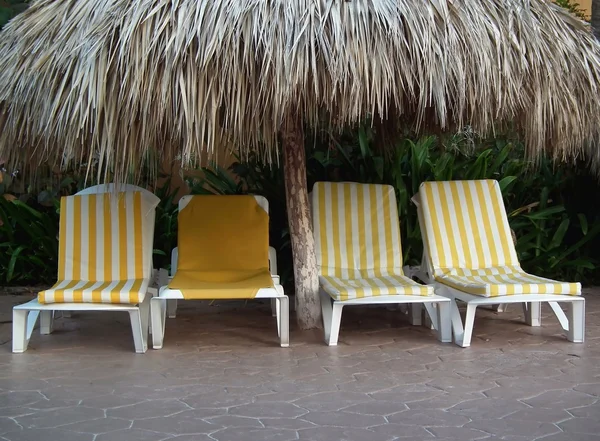 Čtyři polohovací židle pod tropickým chýše — Stock fotografie