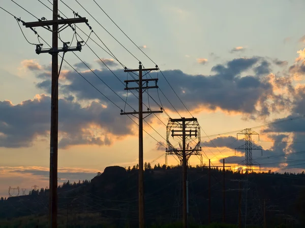 Pólos de energia de madeira e aço ao pôr do sol no país — Fotografia de Stock