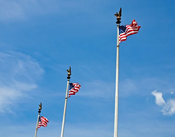Три американских флага гордо машут на высоких флагштоках — стоковое фото