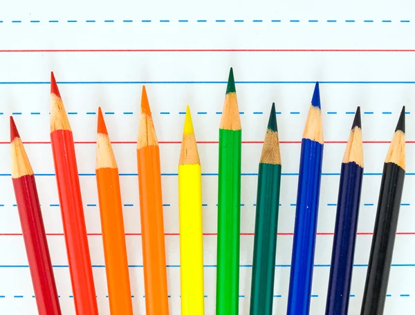 Rainbow çizgili kağıt üzerinde izole renkli kalemler — Stok fotoğraf