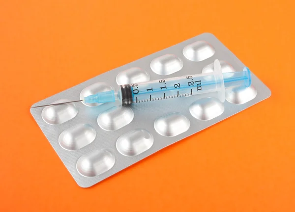 Syringes and tablets on orange — Stock Photo, Image
