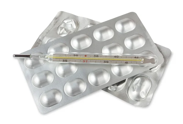 Волдырь с таблетками и термометром изолированы на белом — стоковое фото
