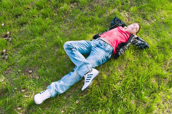 Kluk leží na čerstvé zelené trávě — Stock fotografie