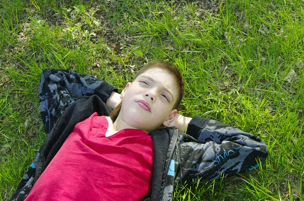 Мальчик лежит на свежей зеленой траве — стоковое фото