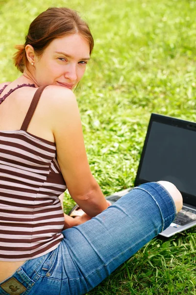 Mujer joven usando su computadora portátil al aire libre. — Foto de Stock