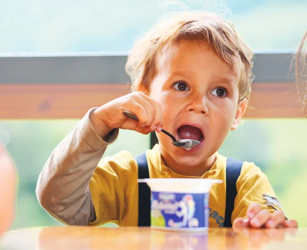 Liten pojke äter yoghurt. — Stockfoto