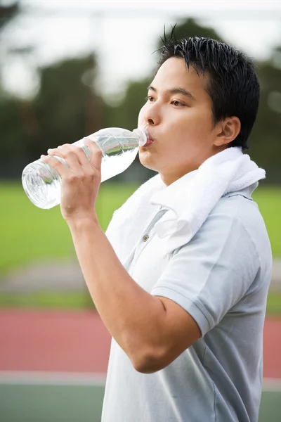 Esportivo asiático macho água potável — Fotografia de Stock