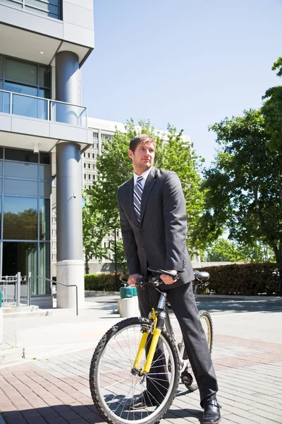 Caucasian businessman riding a bike — Stock Photo, Image