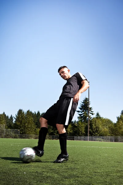 Hispanic soccer or football player kicking a ball — Stock Photo, Image