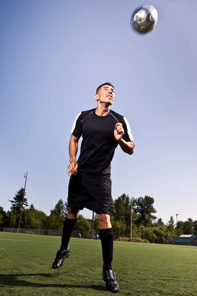 Hispanic soccer or football player heading a ball — Stock Photo, Image