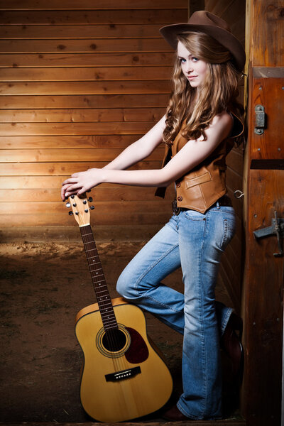 Beautiful caucasian cowgirl with guitar