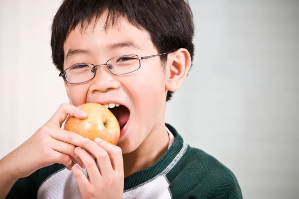 En pojke äter ett äpple — Stockfoto