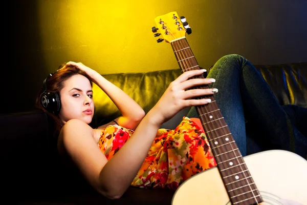 Красивая женщина с наушниками и гитарой — стоковое фото