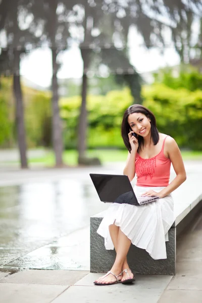Mulher no telefone e trabalhando em seu laptop — Fotografia de Stock