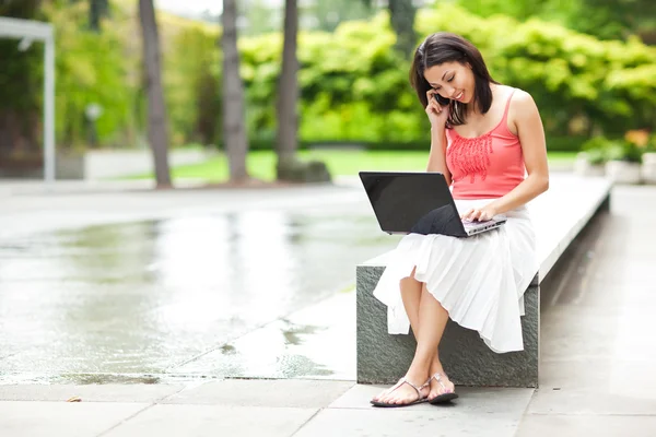 Vrouw op de telefoon en werken op haar laptop — Stockfoto