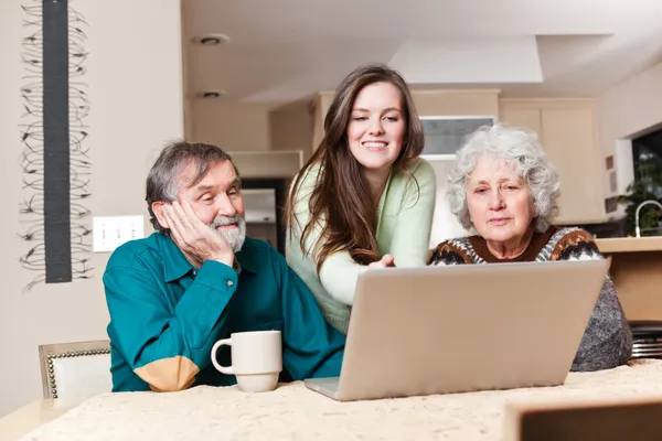 Adolescente chica con abuelos usando el ordenador portátil — Foto de Stock
